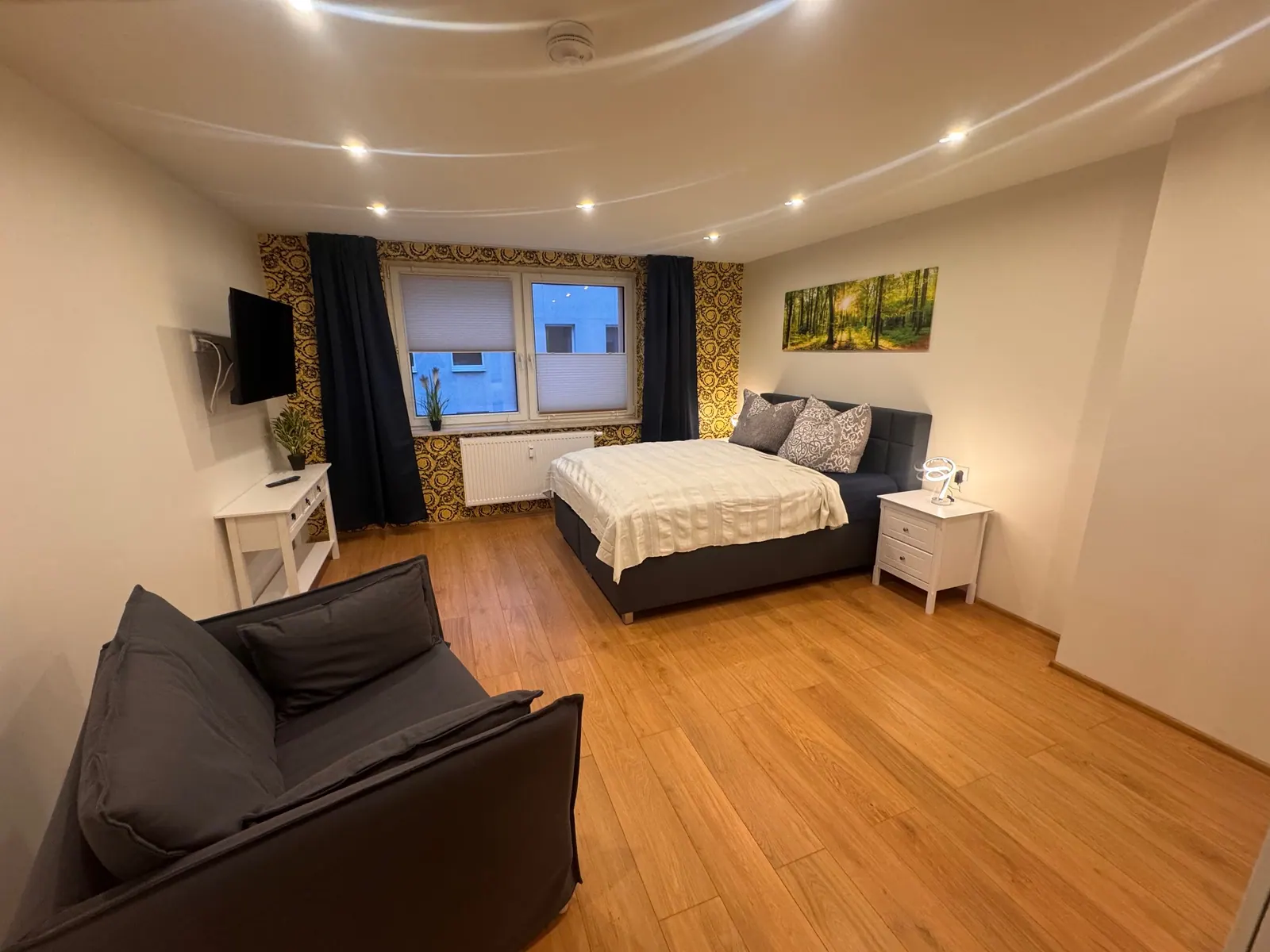Wohnbereich mit Doppelbett, Sofa und Holzboden